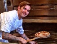 CHEF JEFF MAHIN PUTS PIZZA INTO THE OVEN AT STELLA ROSSA